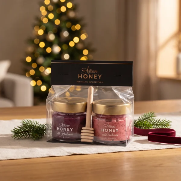 Two-honey gift set with dipper 2 × 100 g – honey with blueberries and honey with cranberries in a warm Christmas gifting setting.