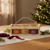 Three-honey gift set in a wooden crate 3 × 100 g – blossom honey, honey with sea buckthorn and honey with wild berries in a warm Christmas gifting setting.