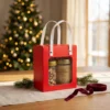 Blossom honey 430 g and honey-salt nuts 170 g in a red gift box with handles in a warm Christmas gifting setting.