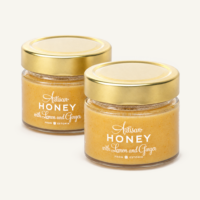 Two jars of Artisan Honey with lemon and ginger, with gold lids.