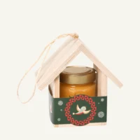 Wooden bird feeder with 300 g honey with sea buckthorn, green sleeve, on a warm light background.