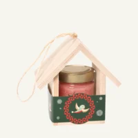 Wooden bird feeder with 300 g honey with strawberries, green sleeve, on a warm light background.