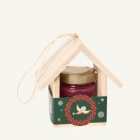 Wooden bird feeder with 300 g honey with wild berries, green sleeve, on a warm light background.