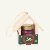 Wooden bird feeder with 300 g honey with blueberries, green sleeve, on a warm light background.