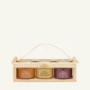 Three 100 g honey jars in a wooden crate: sea buckthorn, blossom honey and wild berries, on a warm light background.